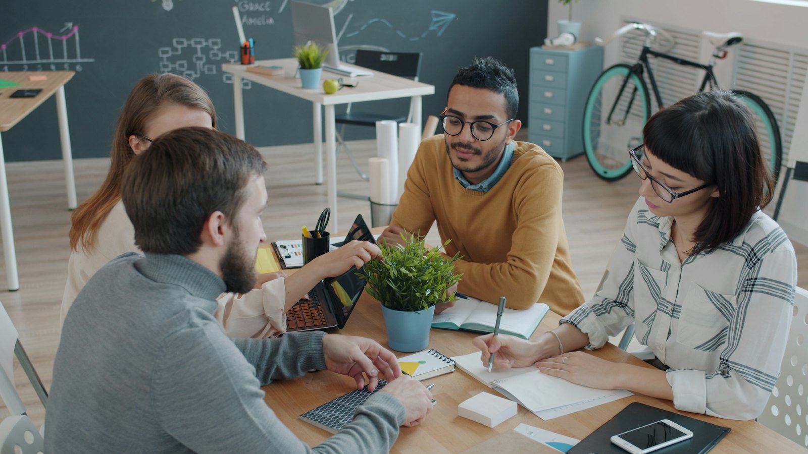 A diverse group of colleagues reviewing work together at a shared desk